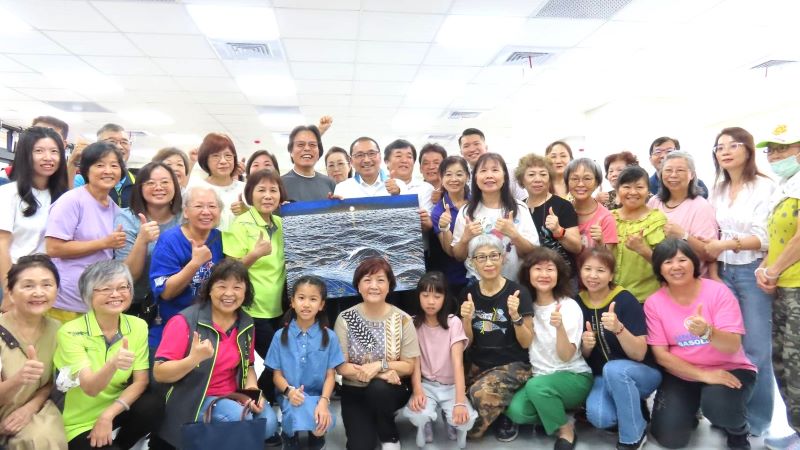 《圖說》侯友宜市長前往活動中心內的繪畫課程,與學員們互動熱絡合影,留下日出畫作。〈民政局提供〉